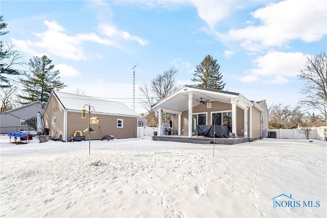 snow covered property with fence and a ceiling fan