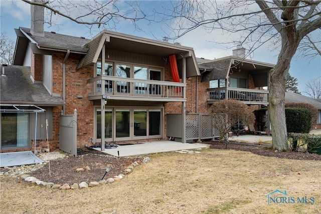 rear view of property with a balcony, a yard, and a patio area