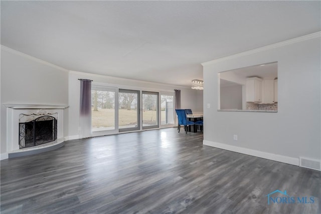 unfurnished living room featuring dark wood-type flooring, a notable chandelier, a premium fireplace, and crown molding