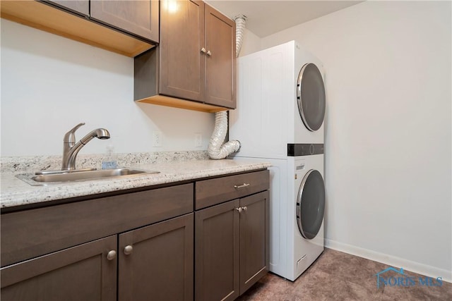 laundry room featuring sink, cabinets, and stacked washing maching and dryer