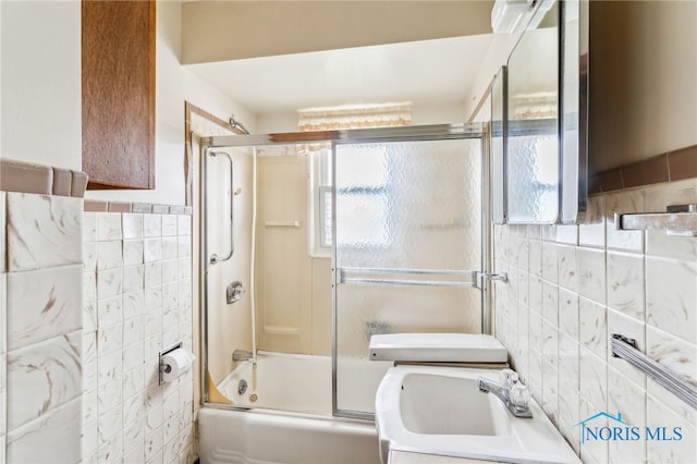 bathroom featuring enclosed tub / shower combo, sink, and tile walls