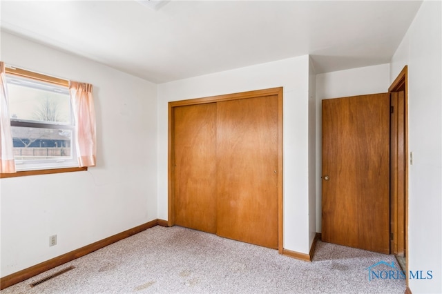 unfurnished bedroom with light colored carpet and a closet