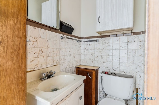 bathroom featuring vanity, tile walls, and toilet