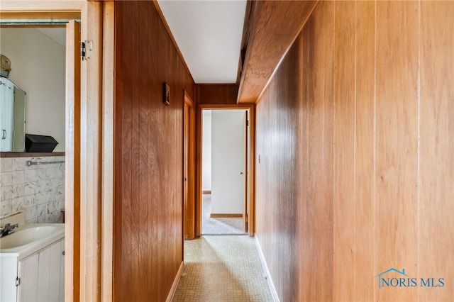 hallway featuring sink and wood walls