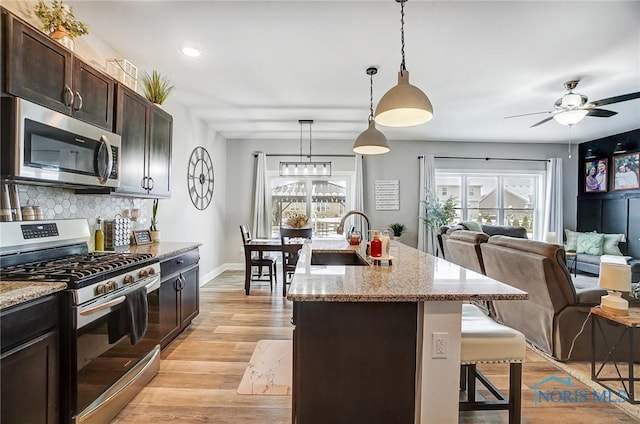 kitchen featuring a breakfast bar, sink, decorative light fixtures, a center island with sink, and stainless steel appliances