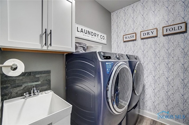 laundry area featuring cabinets, washing machine and dryer, sink, and hardwood / wood-style floors