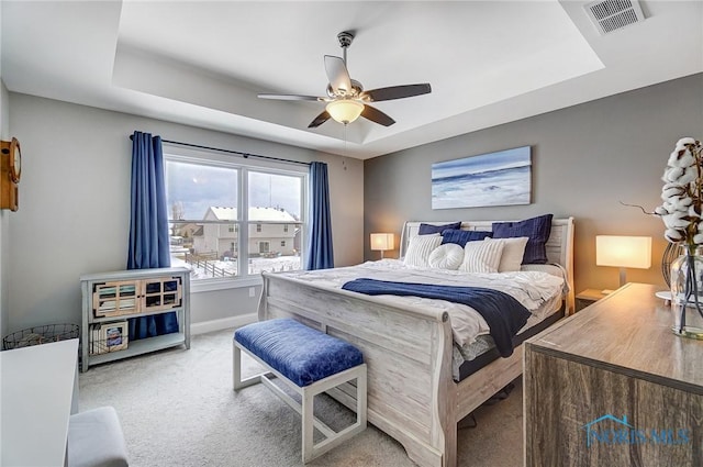 bedroom featuring light carpet, ceiling fan, and a tray ceiling