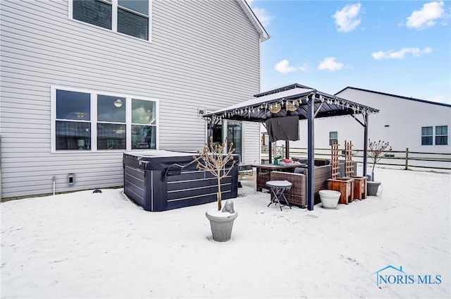 snow covered patio with a gazebo and a hot tub