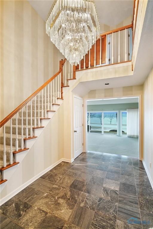 stairs with a towering ceiling and a chandelier