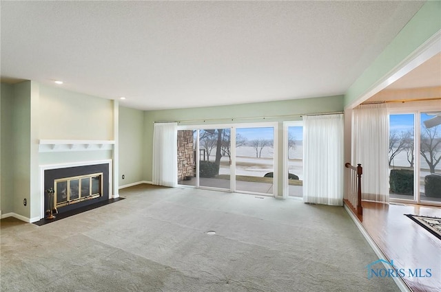 unfurnished living room with carpet floors, a textured ceiling, and a wealth of natural light