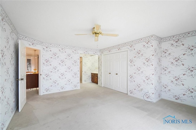 unfurnished bedroom featuring ceiling fan, a closet, ensuite bathroom, and light carpet