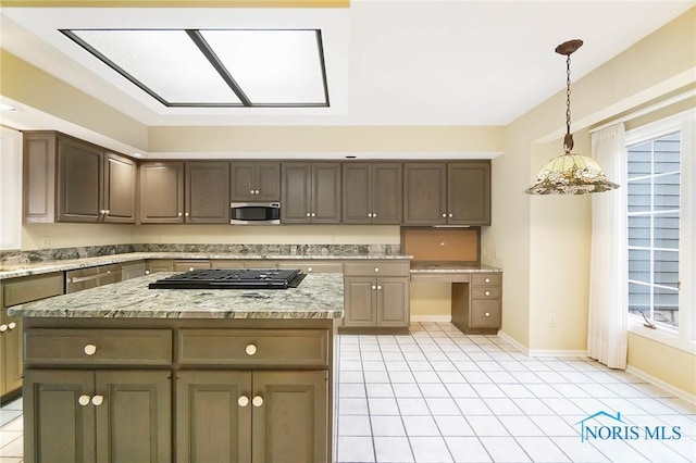 kitchen with hanging light fixtures, a kitchen island, light stone countertops, and appliances with stainless steel finishes