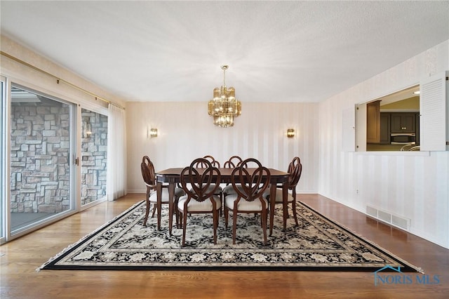 dining room with a textured ceiling, light hardwood / wood-style floors, and a chandelier