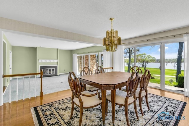 3865 River Rd, Toledo, OH 43614 - dining space featuring an inviting chandelier, a textured ceiling, a glass covered fireplace, baseboards, and a water view