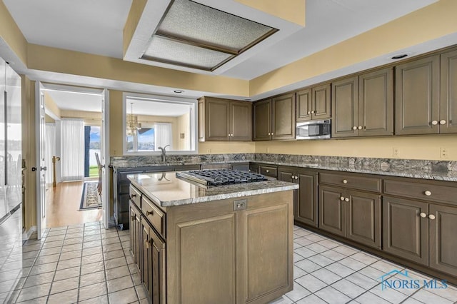 3865 River Rd, Toledo, OH 43614 - kitchen with a center island, gas stovetop, light tile patterned floors, a sink, and stainless steel microwave
