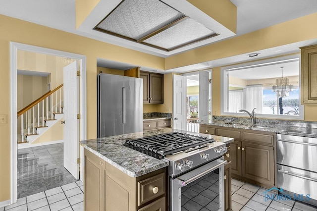 3865 River Rd, Toledo, OH 43614 - kitchen with appliances with stainless steel finishes, a sink, light tile patterned floors, light stone counters, and an inviting chandelier