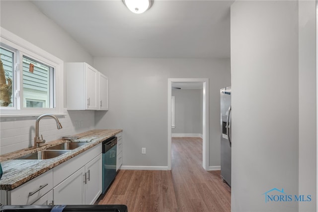 kitchen with white cabinetry, dishwashing machine, sink, and light stone counters