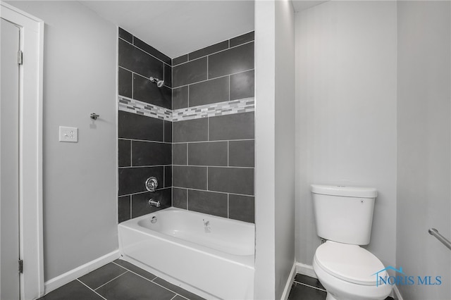 bathroom with tile patterned flooring, tiled shower / bath, and toilet