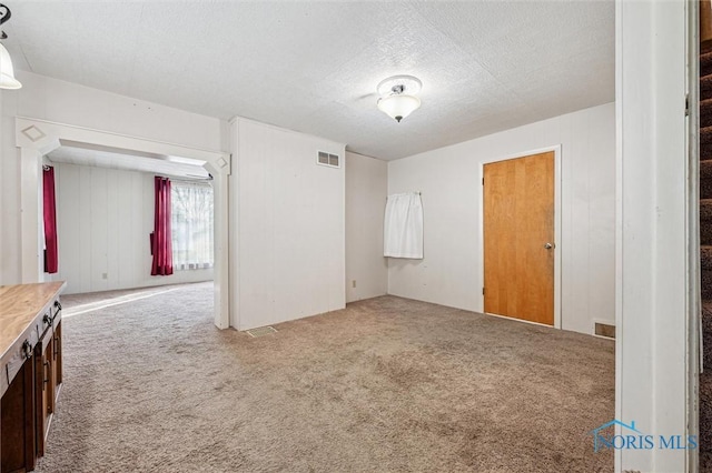 carpeted empty room with a textured ceiling