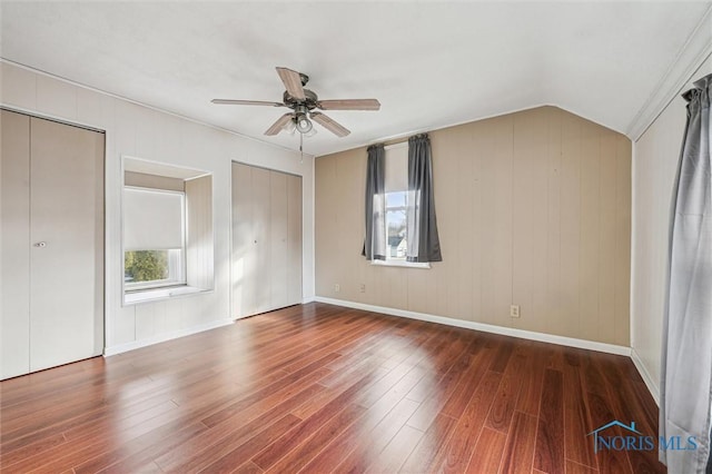 unfurnished bedroom featuring ceiling fan, lofted ceiling, two closets, and dark hardwood / wood-style flooring