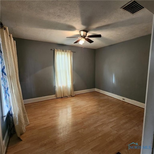 unfurnished room with ceiling fan, hardwood / wood-style floors, and a textured ceiling