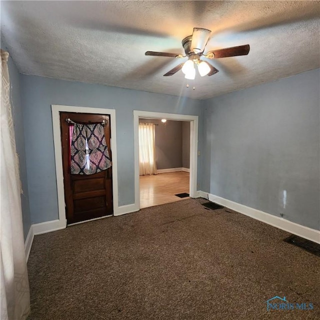 foyer entrance featuring ceiling fan, carpet, and a textured ceiling