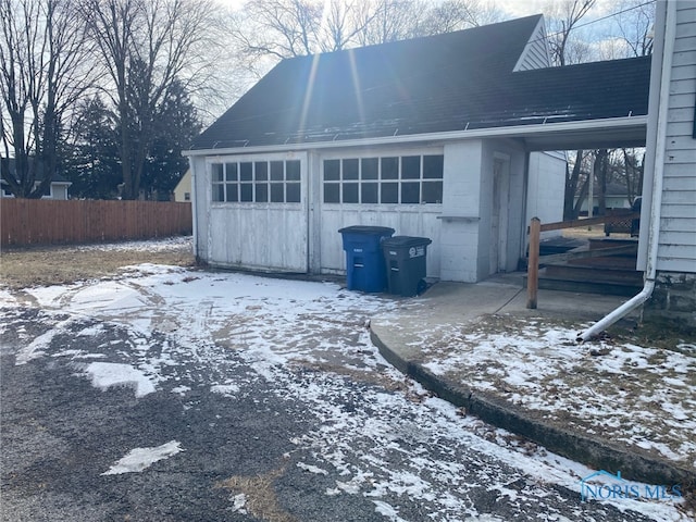 snow covered property featuring an outbuilding and a garage