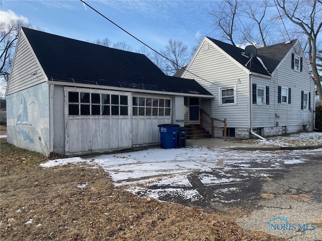 snow covered back of property featuring a garage