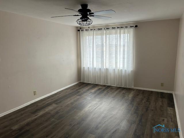 empty room featuring dark wood-type flooring and ceiling fan