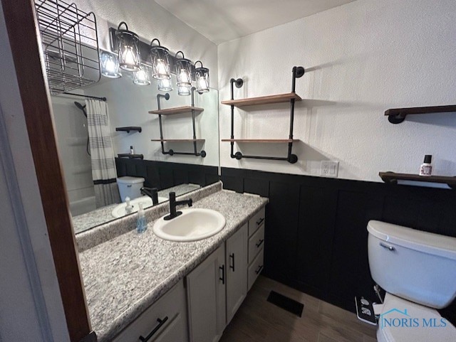 bathroom with hardwood / wood-style flooring, vanity, curtained shower, and toilet