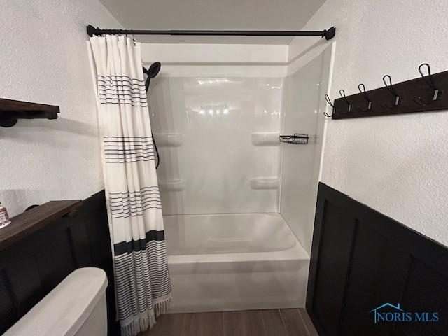 bathroom with hardwood / wood-style floors and shower / bath combo with shower curtain