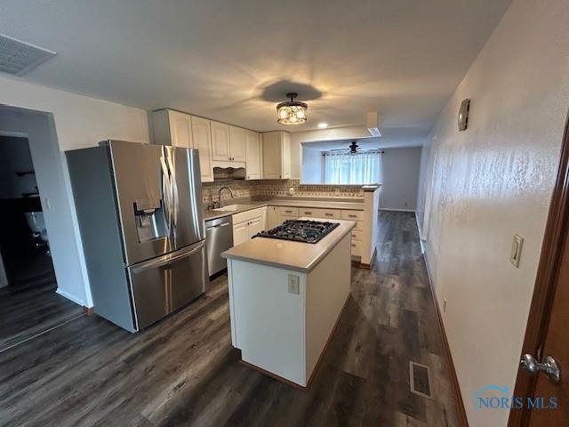 kitchen with dark wood-type flooring, sink, a center island, stainless steel appliances, and white cabinets