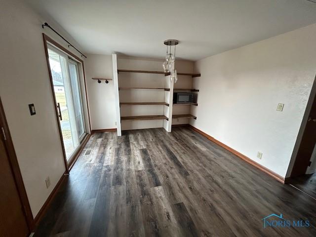 unfurnished living room with dark hardwood / wood-style flooring and an inviting chandelier