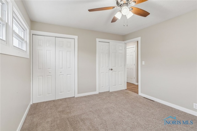 unfurnished bedroom featuring ceiling fan, carpet floors, and multiple closets