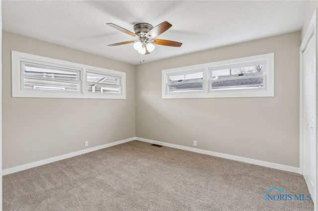 unfurnished room with light carpet, a textured ceiling, a wealth of natural light, and ceiling fan