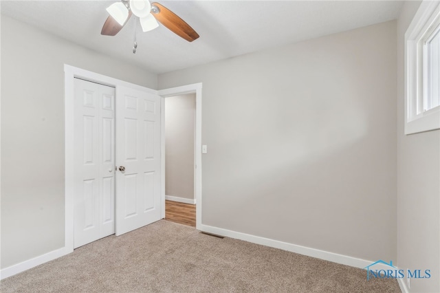 unfurnished bedroom featuring light colored carpet, a closet, and ceiling fan