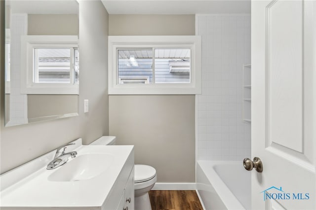 full bathroom featuring tiled shower / bath combo, vanity, wood-type flooring, and toilet