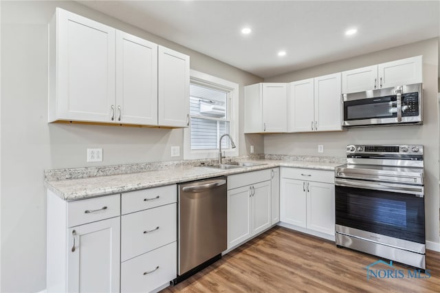 kitchen with white cabinetry, appliances with stainless steel finishes, sink, and hardwood / wood-style flooring