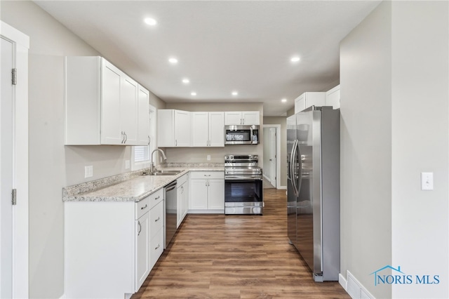 kitchen featuring sink, white cabinetry, light stone counters, dark hardwood / wood-style floors, and stainless steel appliances