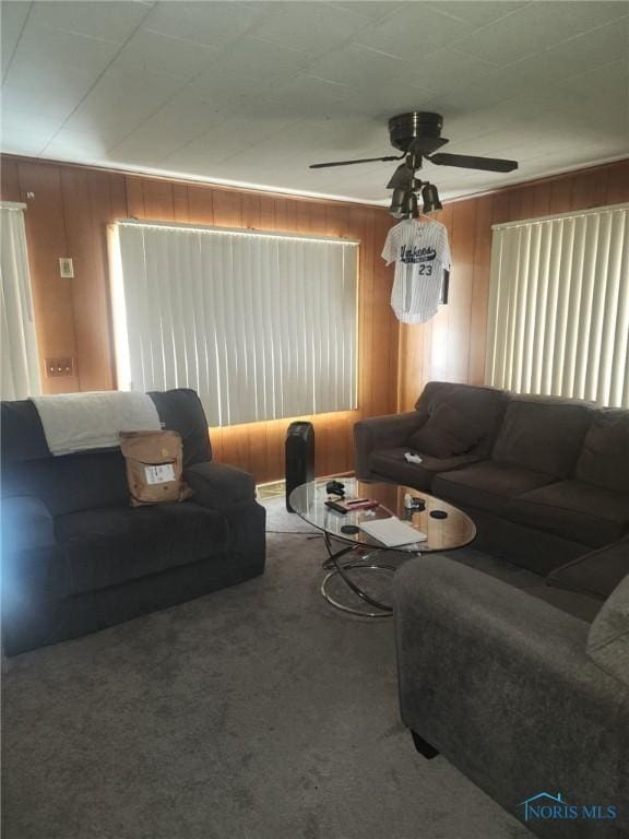 living room with ceiling fan, carpet flooring, and wooden walls