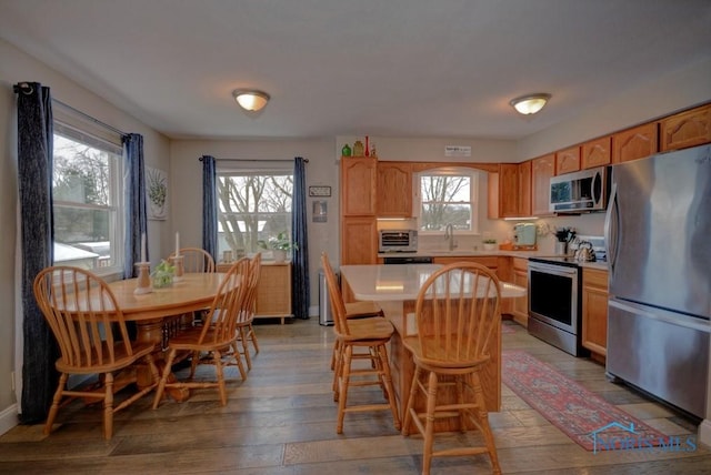 kitchen featuring sink, appliances with stainless steel finishes, hardwood / wood-style floors, a kitchen breakfast bar, and a center island