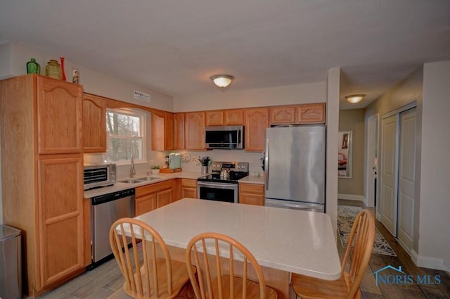 kitchen featuring sink, light brown cabinets, light hardwood / wood-style floors, and appliances with stainless steel finishes