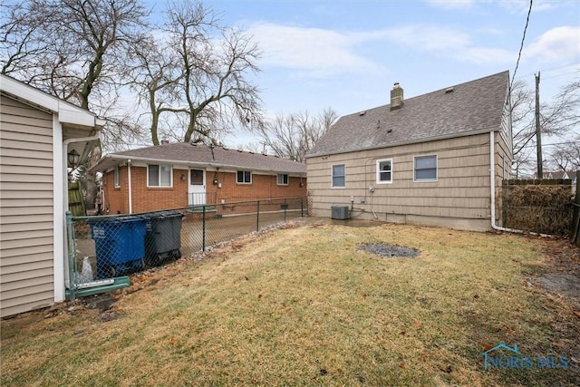 back of property with a yard and central AC unit