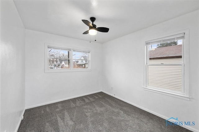 spare room featuring ceiling fan and dark colored carpet