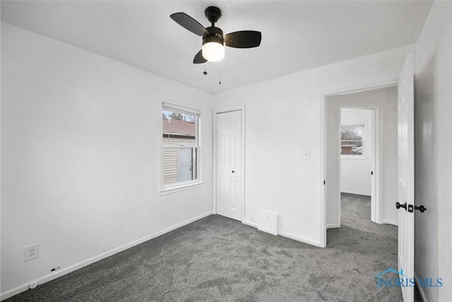 unfurnished bedroom featuring dark colored carpet, ceiling fan, and a closet