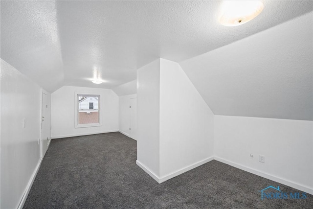 bonus room featuring dark carpet, vaulted ceiling, and a textured ceiling