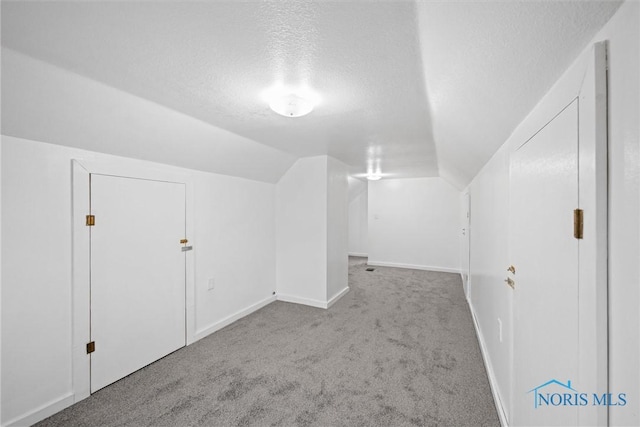 bonus room featuring lofted ceiling, light colored carpet, and a textured ceiling