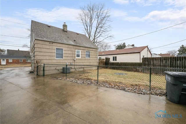 back of house featuring a lawn, central AC unit, and a patio area