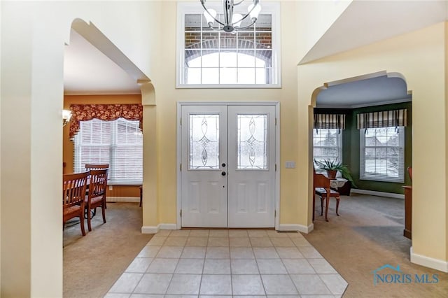 carpeted entrance foyer featuring a towering ceiling and a chandelier