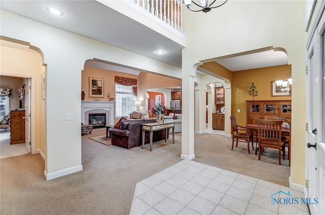 living room with a towering ceiling, decorative columns, and light carpet